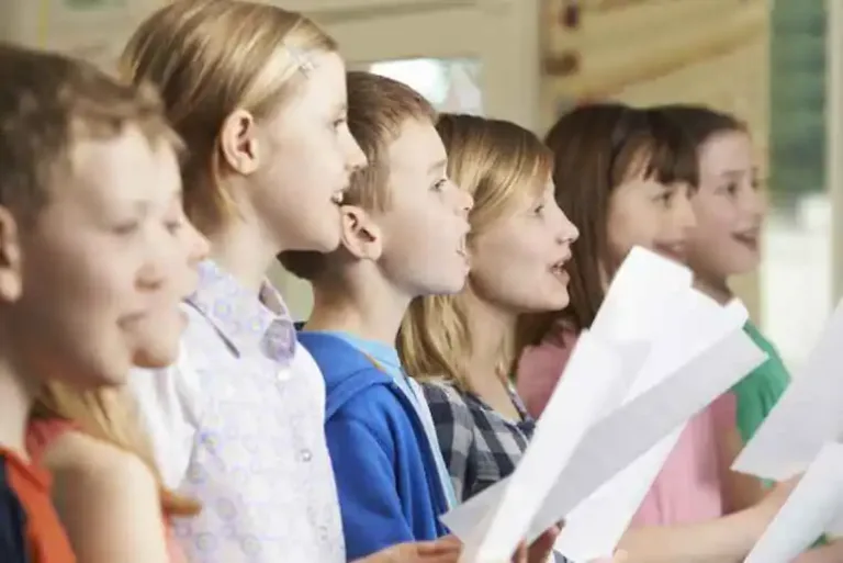 Group of children holding sheet music and singing together in a choir