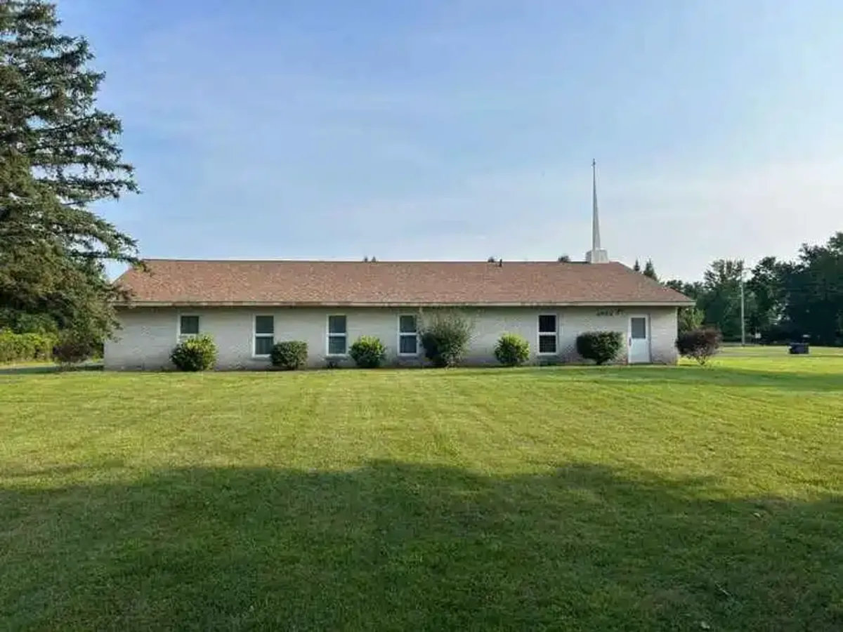 Holt Assembly of God church building with steeple and green lawn in Holt, Michigan.